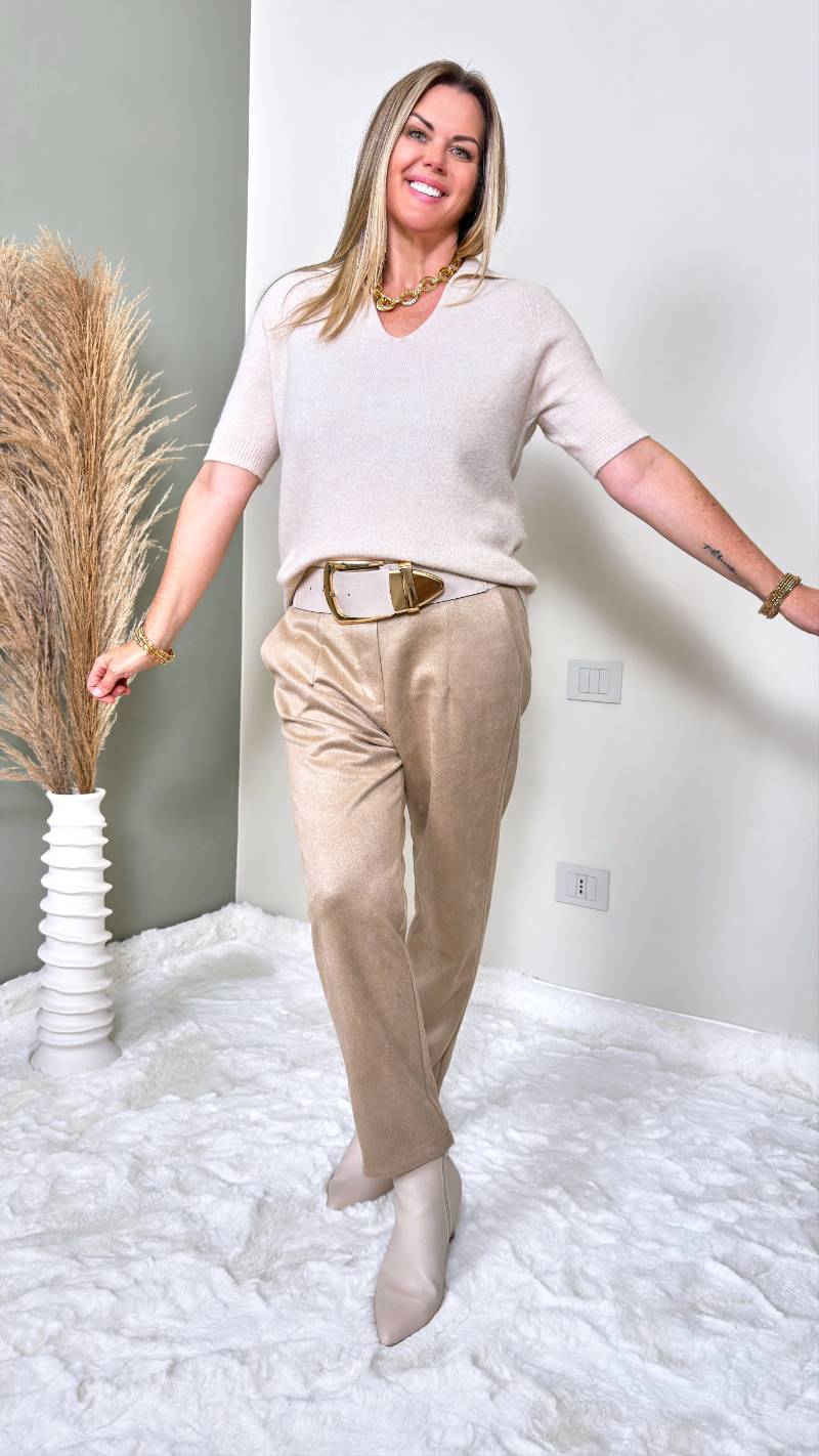 Frau trägt kurzärmeliges Strickshirt mit V-Ausschnitt und Kragen zu heller Stoffhose in Creme