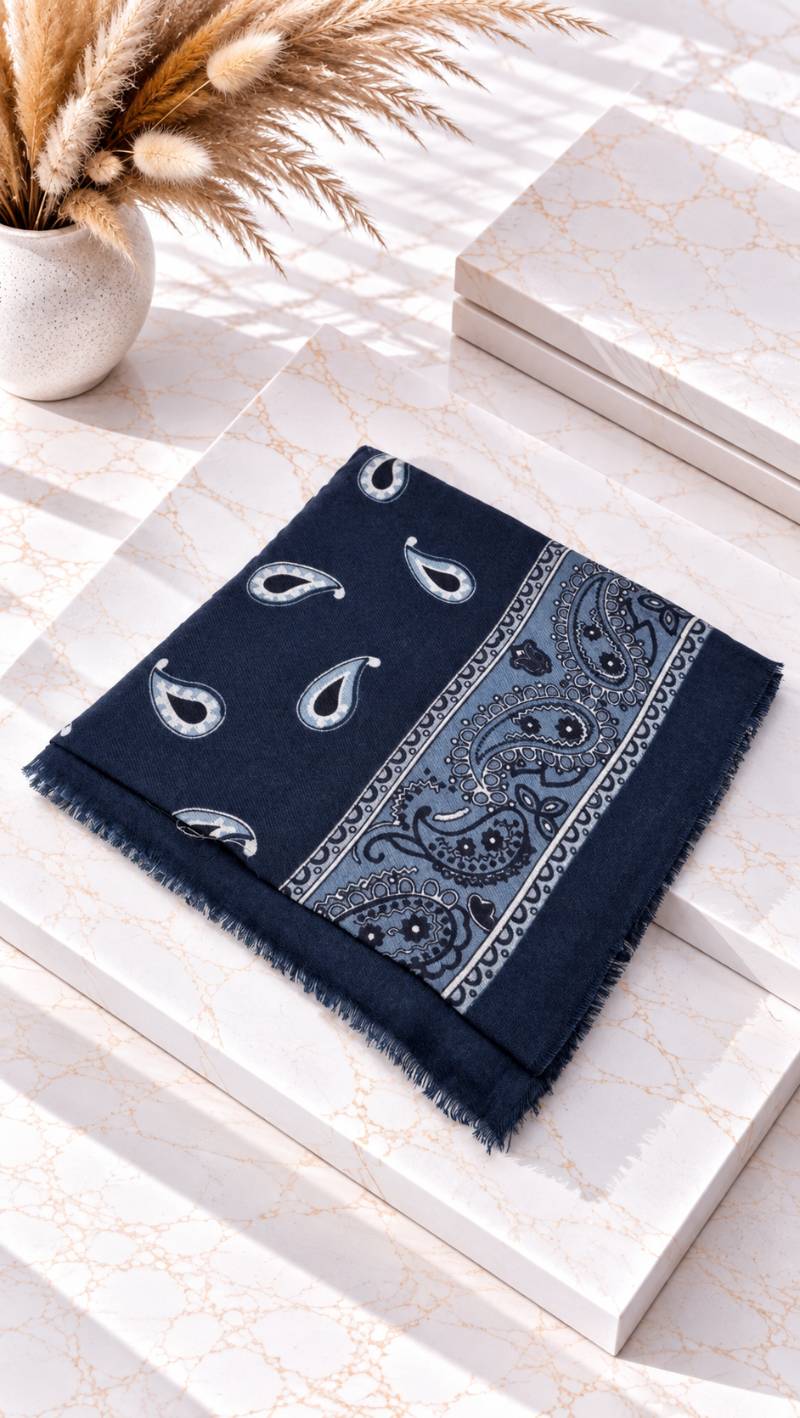 Gefaltetes Tuch mit Paisley-Muster und Fransenkante liegt auf heller Marmorfläche